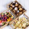 Assorted baked goods and fresh fruit in takeaway boxes from The Moody Chef.