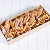 Assorted mini pizzas with toppings in a rectangular box on a white surface.