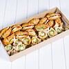 Assorted gourmet sandwiches and wraps in a cardboard box on a white surface.
