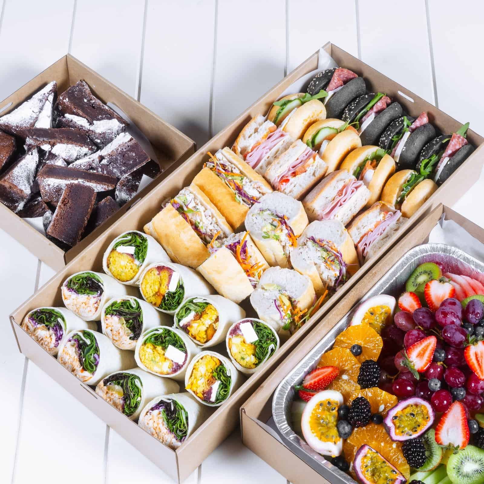 Assorted gourmet sandwiches, desserts, and fresh fruit platter from The Moody Chef.
