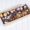 Assorted homemade chocolates and confections in a box on a white surface.