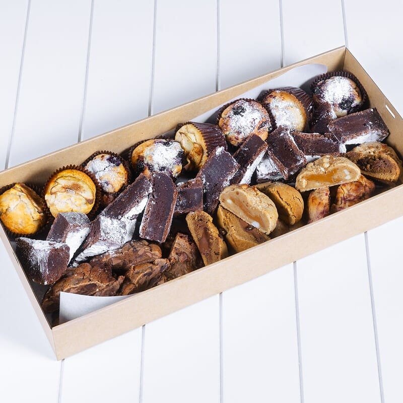 Assorted homemade chocolates and confections in a box on a white surface.