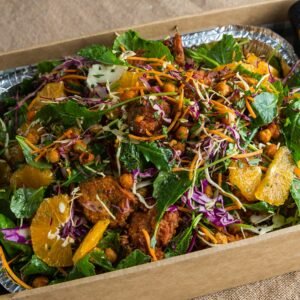Fresh mixed salad with citrus, chickpeas, and greens in a wooden box.