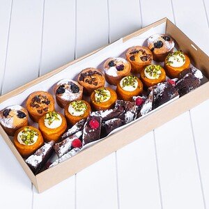 Assorted gourmet mini desserts in a box, including muffins and chocolate treats.