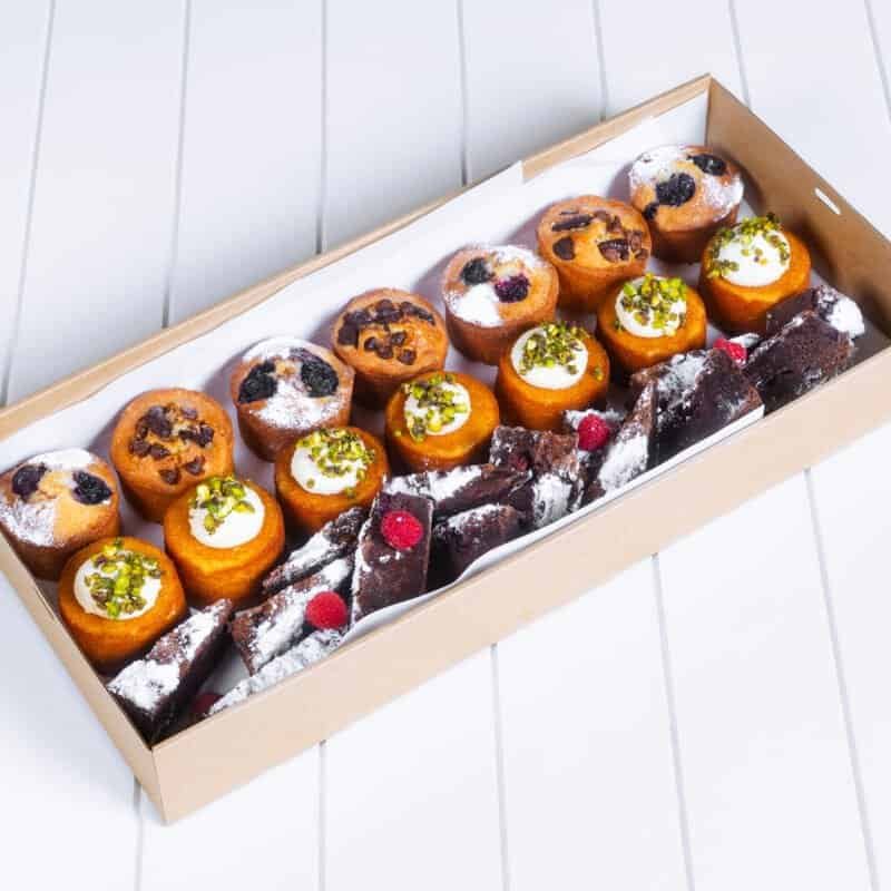 Assorted gourmet mini desserts in a box, including muffins and chocolate treats.
