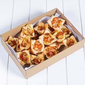 Mini cheese & bacon Quiche in a box on white surface.