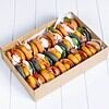 Assorted mini hot dogs in a cardboard tray on a white surface.
