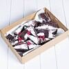 Chocolate brownies with raspberries and powdered sugar in a cardboard tray.