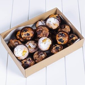 Variety of freshly baked muffins with berries and powdered sugar in a box.