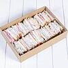 Assorted sandwiches with ham, cheese, and vegetables in a cardboard box.