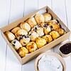 Variety of freshly baked scones with jam and cream on a white table.