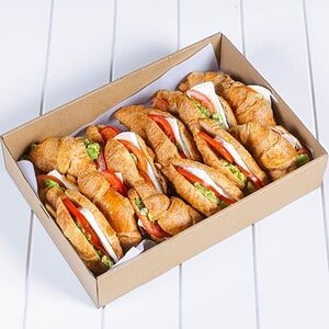 Delicious croissant sandwiches with fresh vegetables in a box.