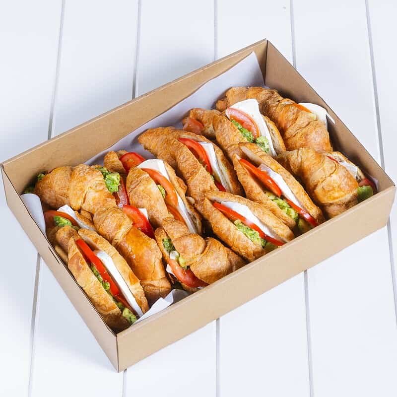 Delicious croissant sandwiches with fresh vegetables in a box.