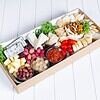 Assorted cheeses, grapes, cherry tomatoes, and cured meats on a cheese board.
